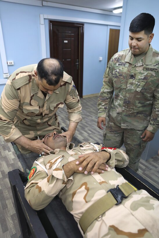 A U.S. soldier observes an Iraqi army soldier conducting medical training.