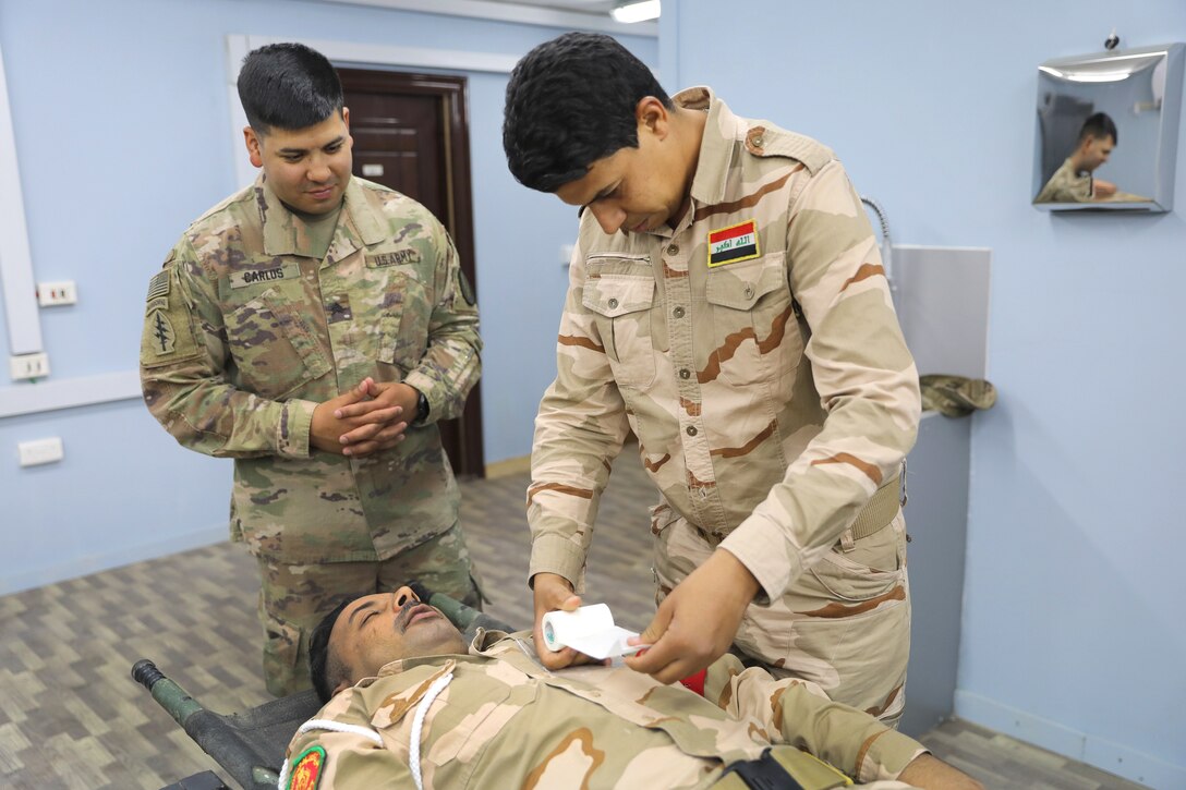 A U.S. soldier observes an Iraqi army soldier conducting medical training.