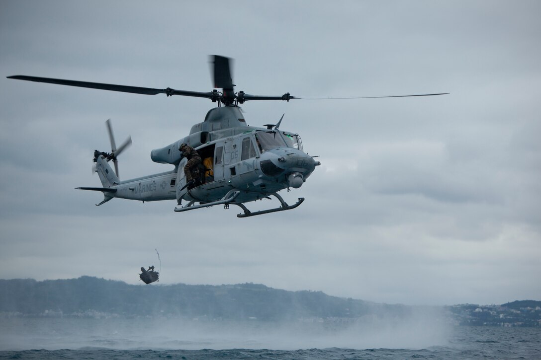 Expeditionary Operations Training Group Marines exit a UH-1Y Venom helicopter during helocast training, June 1, 2018, near White Beach Naval Facility, Okinawa, Japan. Once Marines receive a signal from the helicopter crew chief, they must drop their flotation devices and jump into the drop zone. (U.S. Marine Corps photo by Lance Cpl. Zackary Walker)