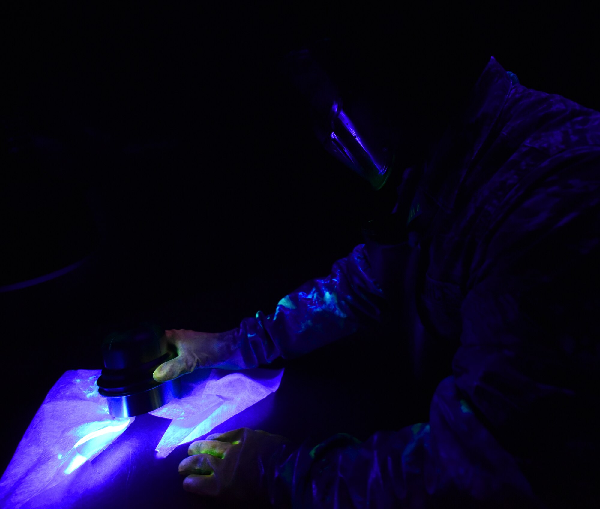 A U.S. Air Force nondestructive inspection specialist from the 325th Maintenance Squadron, inspects a metal component under a black light at Tyndall Air Force Base, Fla., May 23, 2018. Fluorescent chemicals are used to help identify small cracks or stresses on metal equipment and systems that may lead to accidents. (U.S. Air Force photo by Senior Airman Cody R. Miller/Released)
