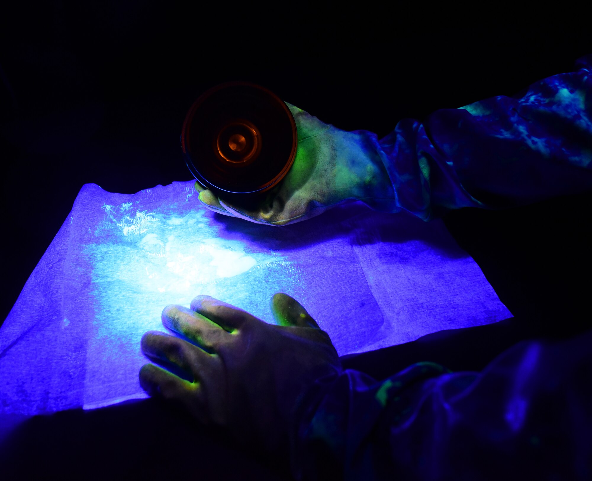 A U.S. Air Force nondestructive inspection specialist from the 325th Maintenance Squadron inspects a metal component under a black light at Tyndall Air Force Base, Fla., May 23, 2018. Utilizing everything from x-rays to ultrasound, nondestructive inspection specialists find the smallest imperfections and take the corrective measures needed to keep Air Force equipment working safely. (U.S. Air Force photo by Senior Airman Cody R. Miller/Released)