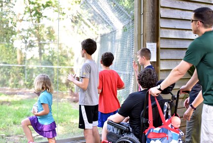 Lt. Col. Bryan Collins, 628th Comptroller Squadron commander, and his family look into the cage of red wolves during an Exceptional Family Member Program event June 1, 2018, at the Charles Town Landing Zoo.