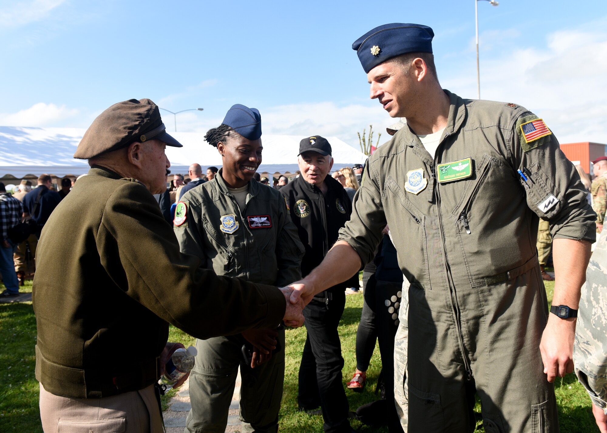 World War 2 survivor wearing World War 2 uniform shakes hands with Man in current Air Force flightsuit