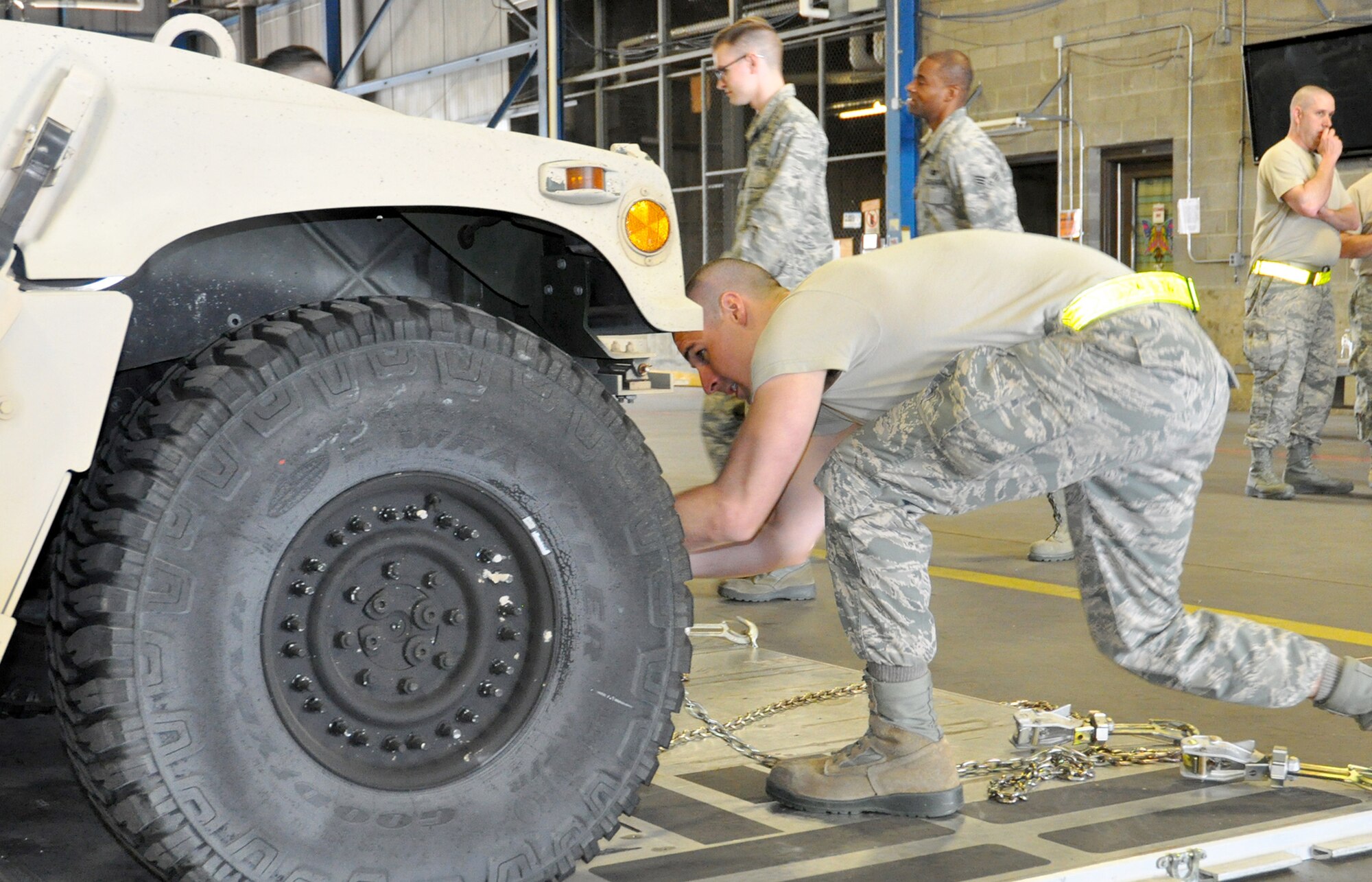 Tech. Sgt. Eric Wadlington, 87th Aerial Port Squadron special handling technician, works to quickly attach a chain to the tie-down point of a Humvee, simulating how a vehicle must be secured to the floor of an aircraft May 5, 2018. Wadlington was one of several team members working to secure the vehicle as judges observed for safety violations and technical errors during the Port Dawg Challenge May 5, 2018.