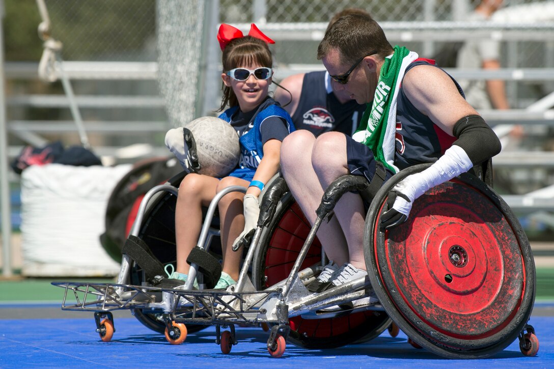 A child and an adult in a wheelchair play rugby.