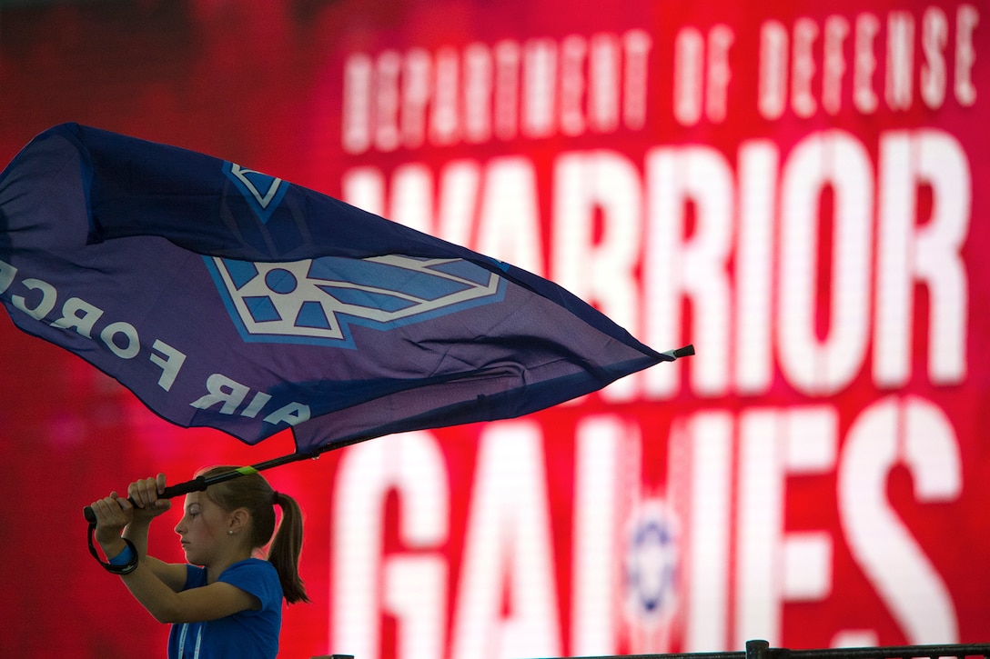 A girl waves an Air Force flag to support athletes competing in an air rifle competition during the 2018 DoD Warrior Games
