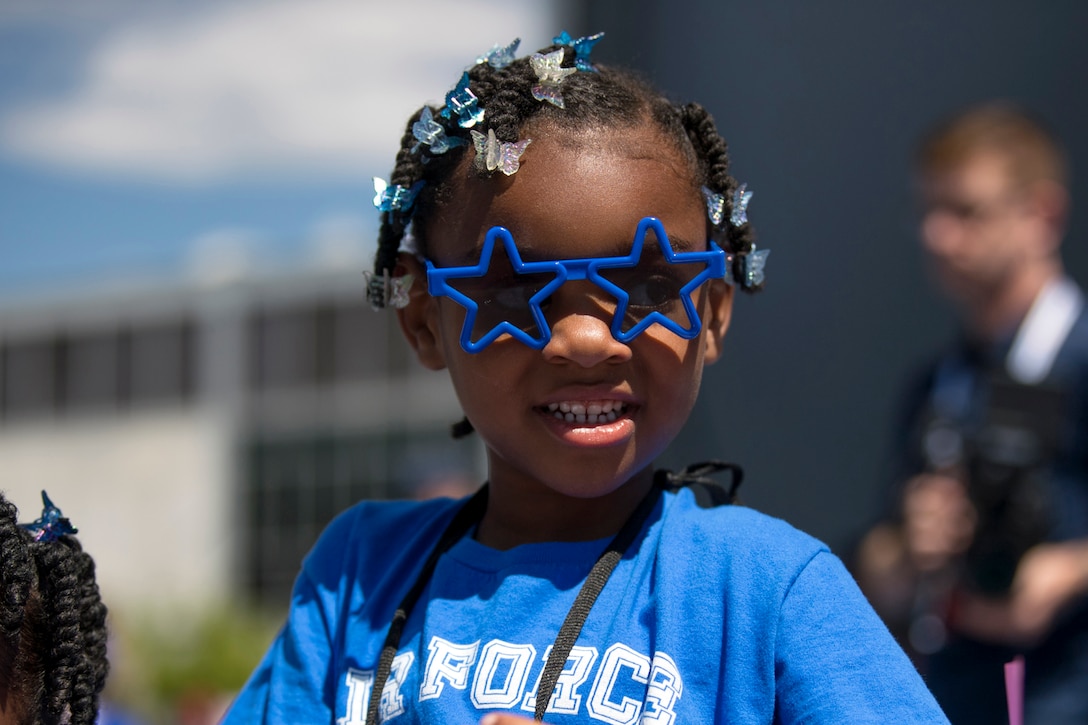 A child wears decorative glasses and ribbons during an exhibition day for families.