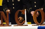 Three NCOs acting on behalf of NCOs of the past, present and future light three candles. The red candle represents valor, the white honor and integrity, and the blue vigilance.
