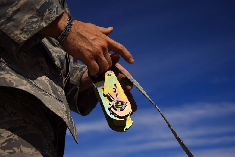 Tech. Sgt. Robert Brousseau, 99th Civil Engineer Squadron explosive ordnance disposal technician, unwinds a strap during an ammunitions disposition request at Nellis Air Force Base, Nevada, May 31, 2018. Ammunition disposition requests serve as a way for the Nevada Division of Environmental Protection to permit Nellis AFB to properly destroy munitions determined to be unsafe for transportation or storage. (U.S. Air Force photo by Airman 1st Class Andrew D. Sarver)