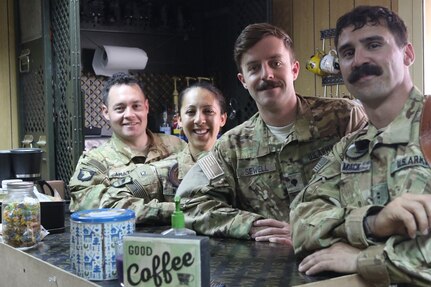 U.S. Army Chief Warrant Officer 2 Ryan Amato, Capt. Ashley Morris, Spc. Toby Sewell and Chief Warrant Officer 2 David Mack assigned to 1st Battalion, 189th Aviation Regiment, stand left to right behind the Dustoff Coffee shop bar at Camp Taji, Iraq, May 18, 2018. Creating or taking over a coffee shop while deployed is an Oregon National Guard tradition. The donation-based business provides funds for Soldiers in order to boost morale and build unit cohesion.