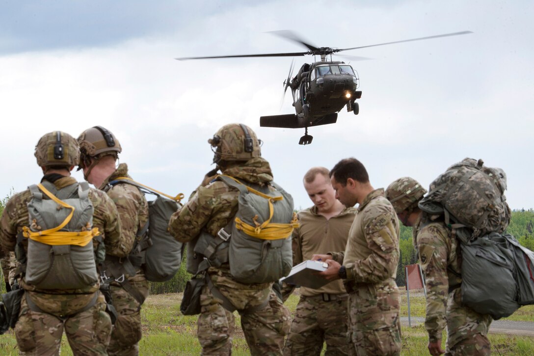 Airmen and soldiers wait for an approaching UH-60 Black Hawk helicopter.