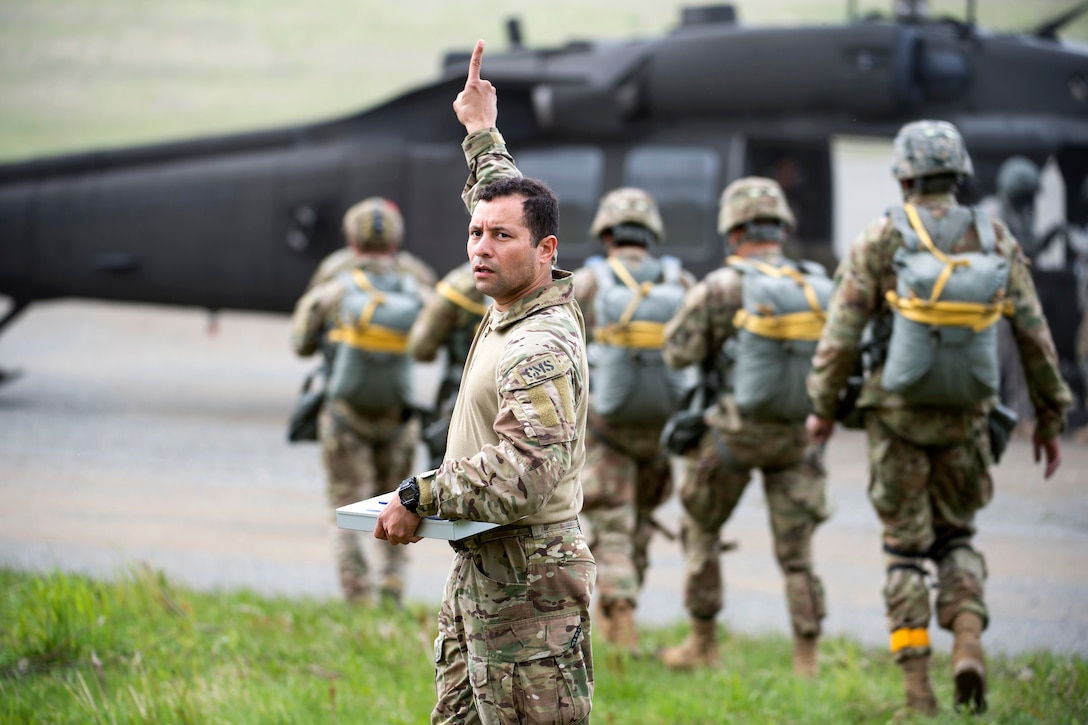 An airman directs personnel to awaiting UH-60 Black Hawk helicopters.