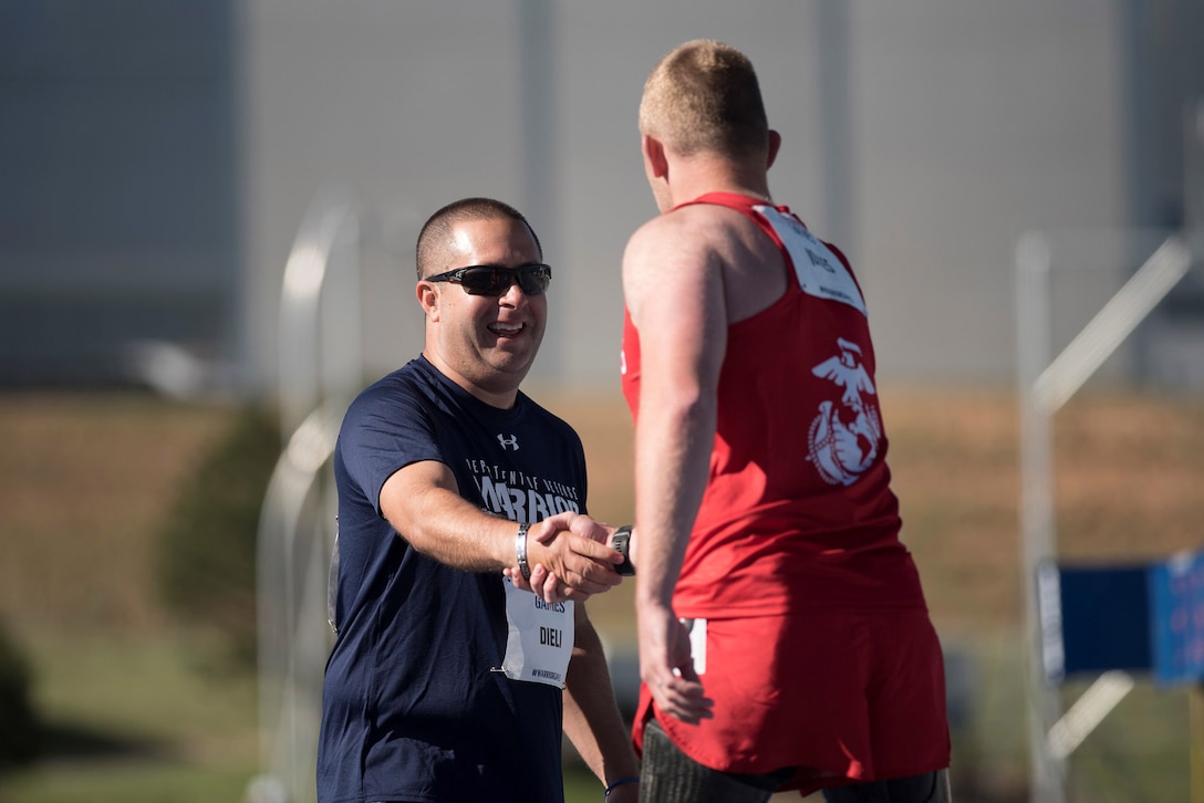 Medically retired Navy Petty Officer 3rd Class Anthony Dieli is congratulated by Marine Corps veteran Sgt. Robert Jones after they ran a 400-meter race during the 2018 Defense Department Warrior Games at the U.S. Air Force Academy in Colorado Springs, Colo., June 2, 2018. Established in 2010, the annual Warrior Games introduce wounded, ill and injured service members to adaptive sports as a way to enhance their recovery and rehabilitation. DoD photo by Roger L. Wollenberg