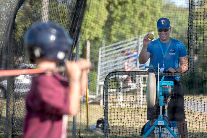 A person holds a ball and a child holds a bat.