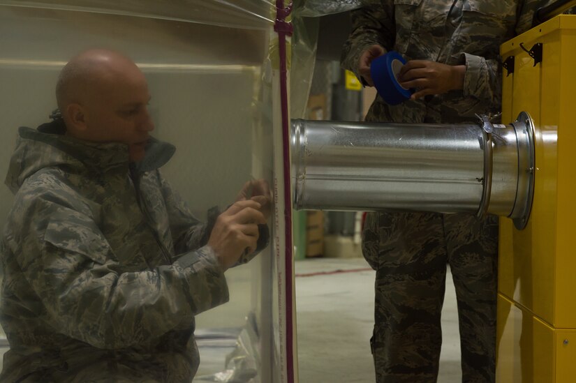 U.S. Air Force Staff Sgt. Mathew Footit, 633rd Aerospace Medicine SquadU.S. Air Force Master Sgt. Alexander Gonzalez, 1st Maintenance Squadron low observable section chief, cuts an opening for the “Tent & Vent” system at Joint Base Langley-Eustis, Virginia, March 2, 2018.