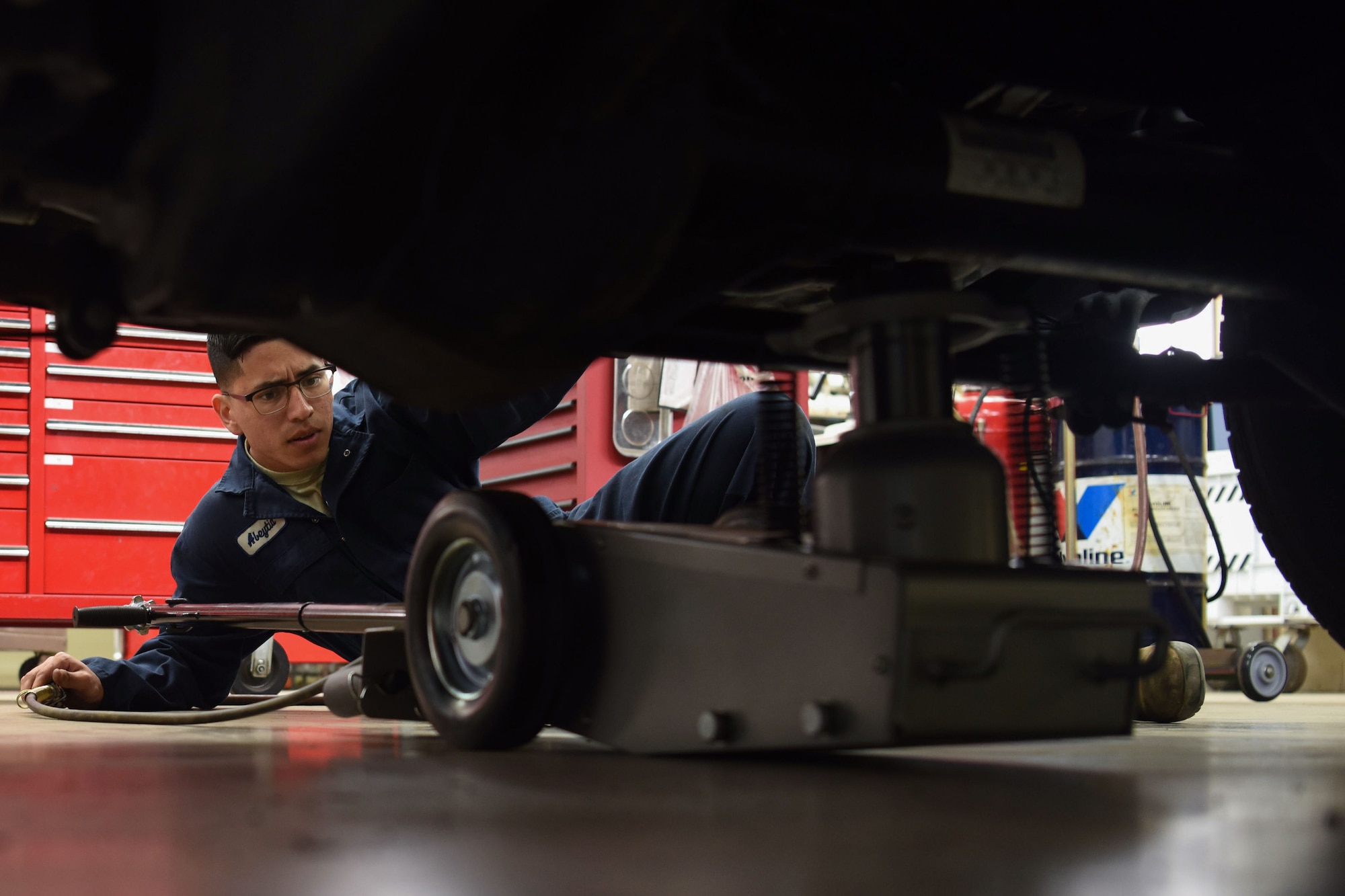 Airman 1st Class Jacobo Abeytia, 30th Logistics Readiness Squadron vehicle maintenance apprentice, places a jack underneath a vehicle during a routine tire change, May 29, 2018, at Vandenberg Air Force Base, Calif. Abeytia lifted the vehicle to begin the tire change. (U.S. Air Force photo by Airman Aubree Milks/Released)
