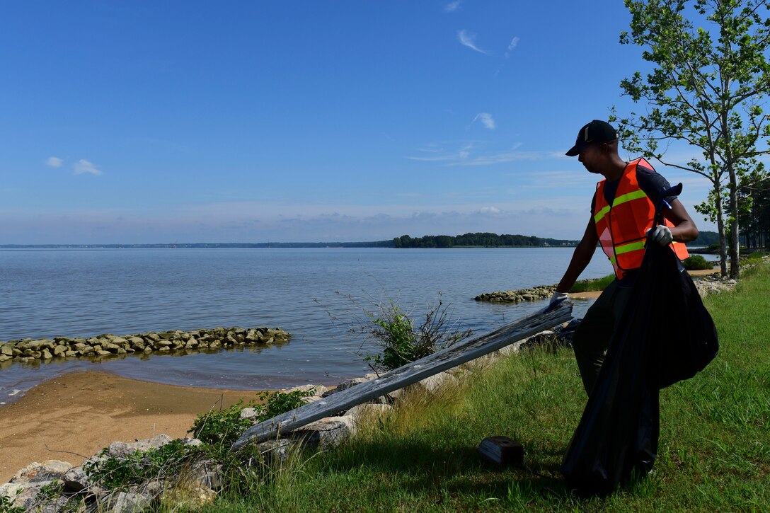 U.S. Air Force Capt. Gregg Johnson, 45th Intelligence Squadron flight commander, picks up a plank of wood during Clean the Bay Day at Joint Base Langley-Eustis, Virginia, June 2, 2018. During event, volunteers picked up trash and debris along the James River shoreline at Fort Eustis. (U.S. Air Force photo by Airman 1st Class Monica Roybal)