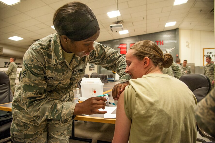 Senior Airman Rocquisha Locke inoculates Airman 1st Class Kadienne Simons during an Individual Medical Readiness activity May 24