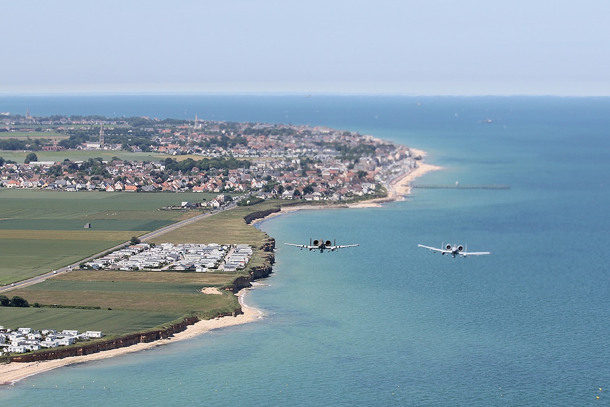 Two aircraft fly along a coastline.