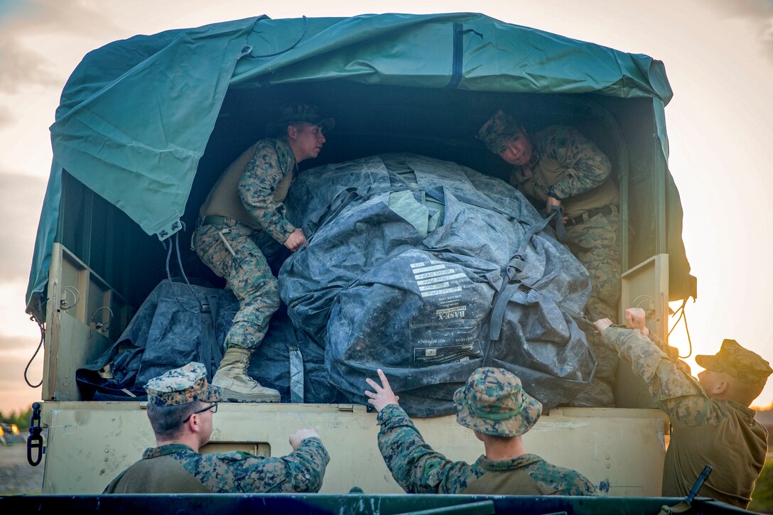 Marines in a truck pass tents to Marines outside a truck.