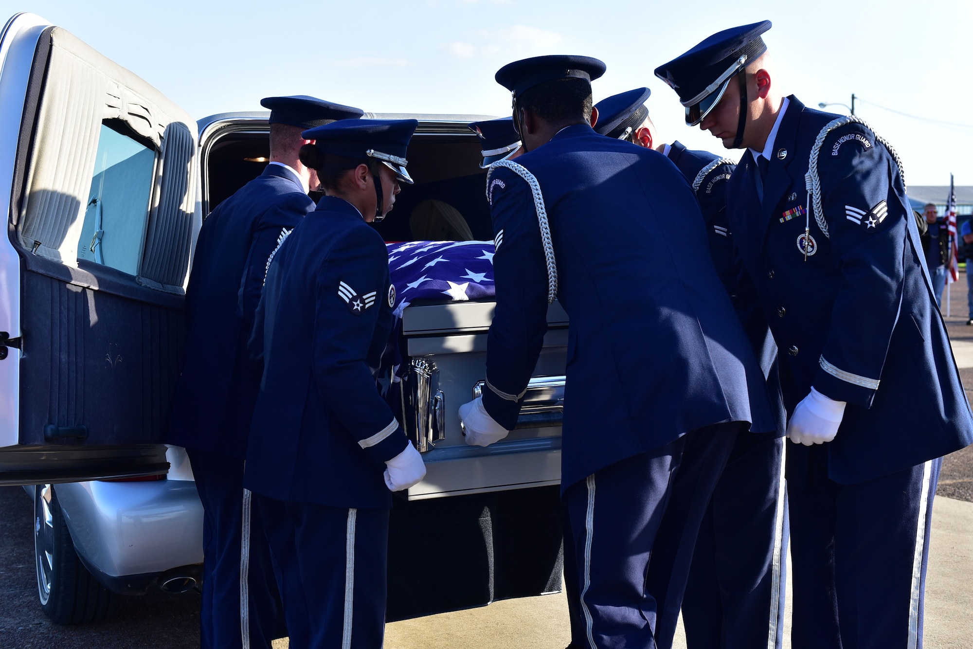 Airmen load a coffin onto the back of a hearse.