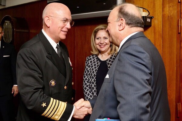 Navy Adm. Kurt W. Tidd shakes hands with Colombia's defense minister in a wood-paneled room.