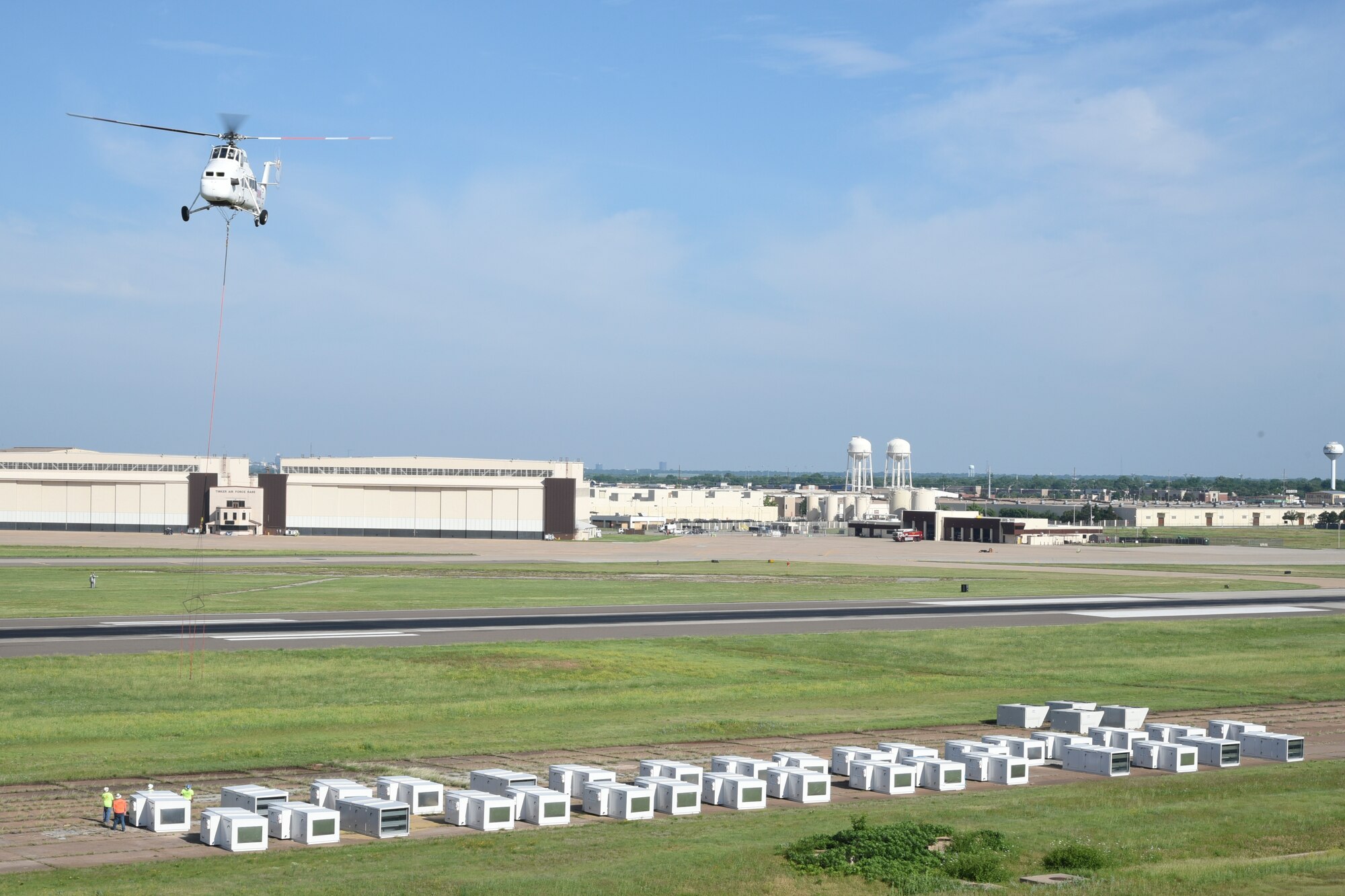 A Sikorsky S-58 heavy-lift helicopter hovers over heating units being moved to the roof of building 3001 as part of on-going energy efficiency upgrades taking place across Tinker Air Force Base, Oklahoma on May 27, 2018.