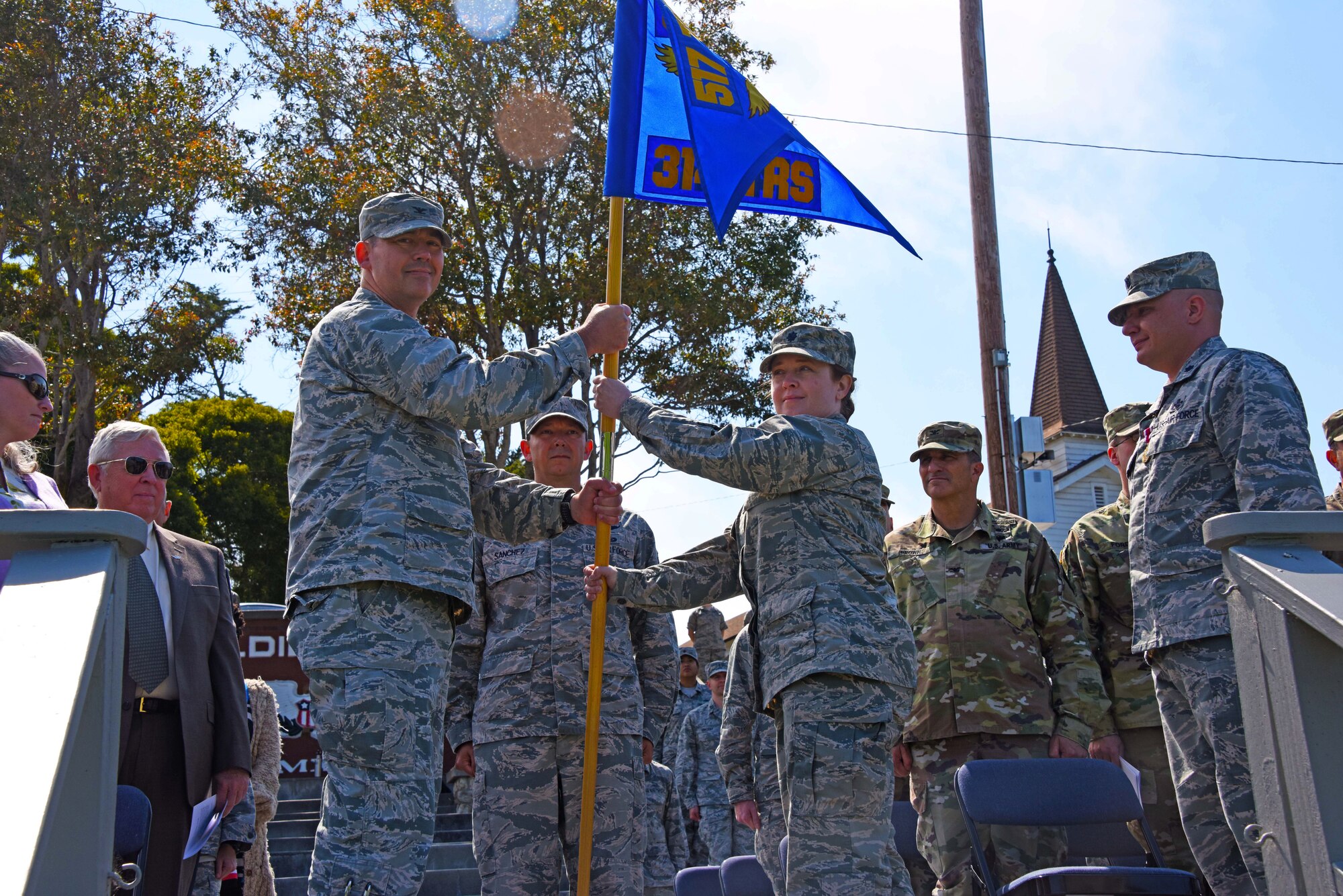 U.S. Air Force Col. Wiley Barnes, 517th Training Group Commander, passes the 314th Training Squadron guideon to Lt. Col. Jaclyn DeRoush, 314th TRS incoming commander, at the 314th TRS Change of Command at the Presidio of Monterey, California, June 6, 2018. The guideon signifies the passing of command from one commander to the next. (U.S. Army photo by Natela Cutter/Released)