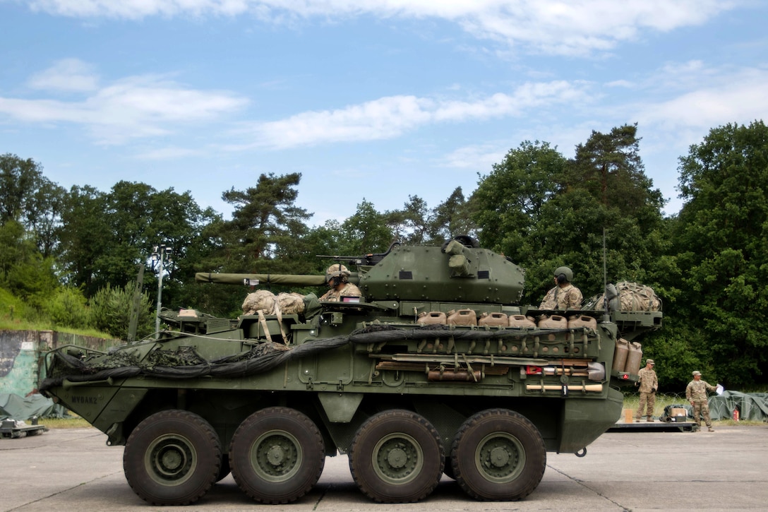 Soldiers maneuver their M1126 Stryker combat vehicle to receive ammunition.