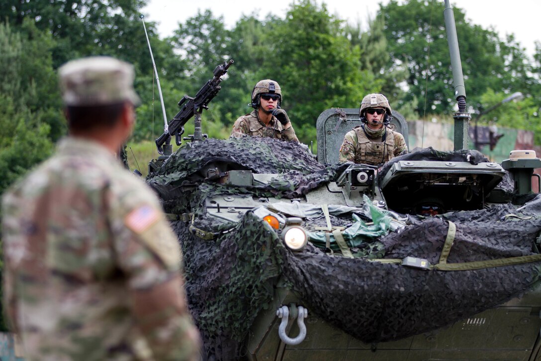 A soldier ground guides a M1126 Stryker combat vehicle to receive ammunition.