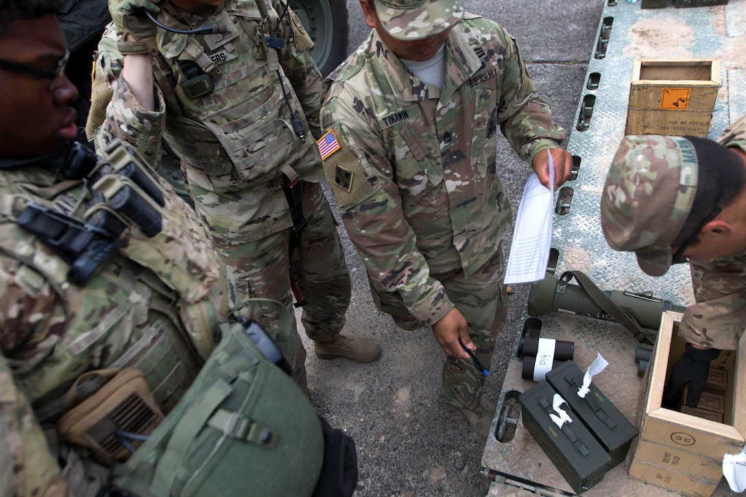 A soldier counts the number of ammunition rounds being passed out.
