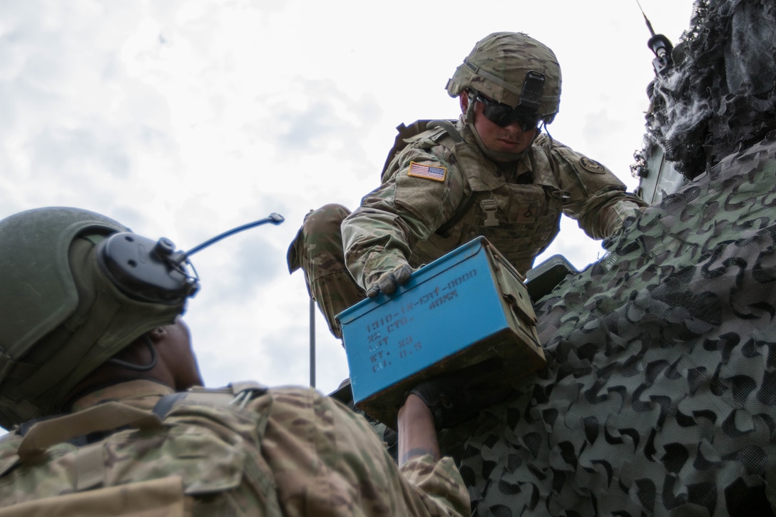 Soldiers load cans of ammunition onto their M1126 Stryker combat vehicle.