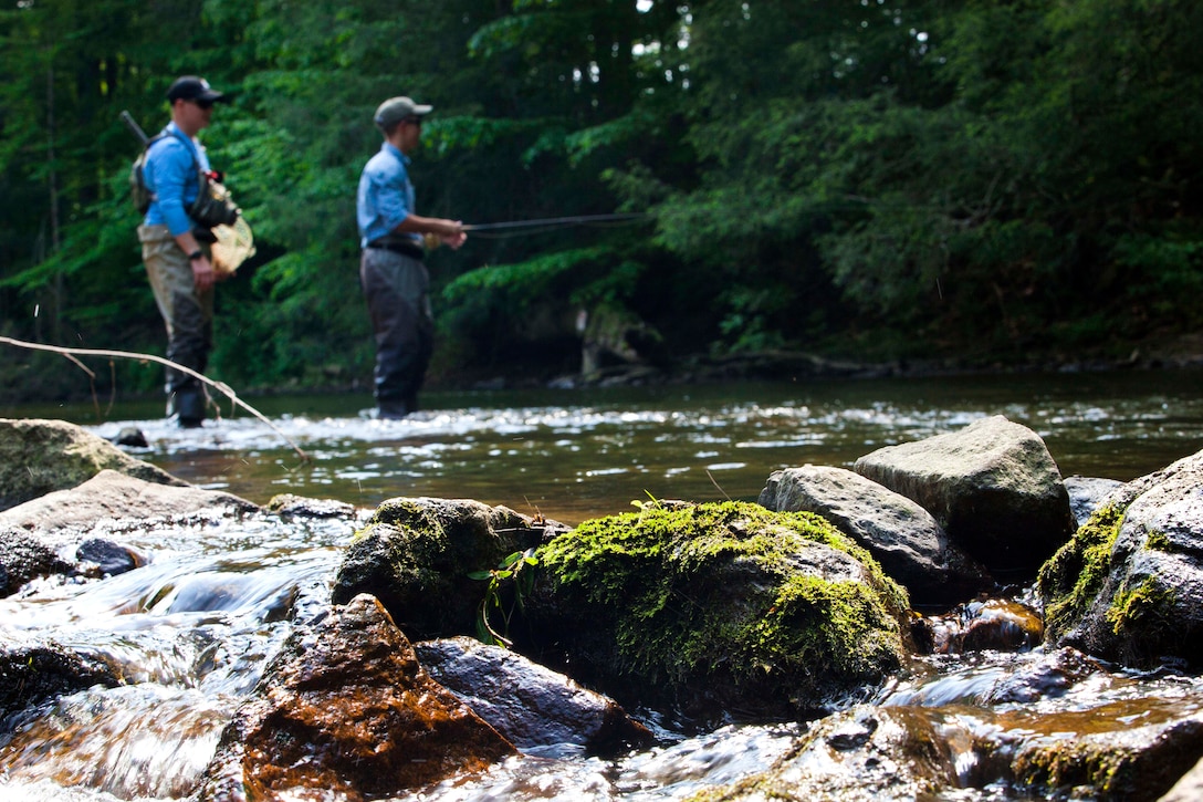A Marine receives fishing instructions from a volunteer fly fishing guide.