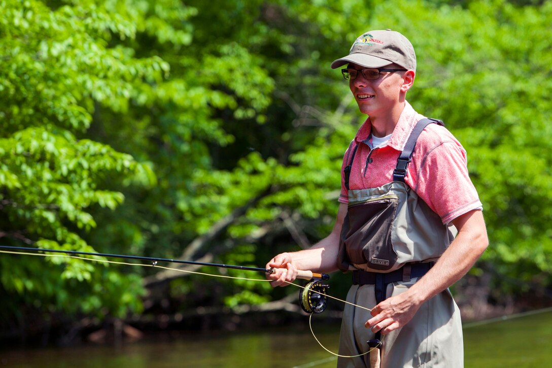 A Marine tightens up his line after a successful cast during a fly fishing event.