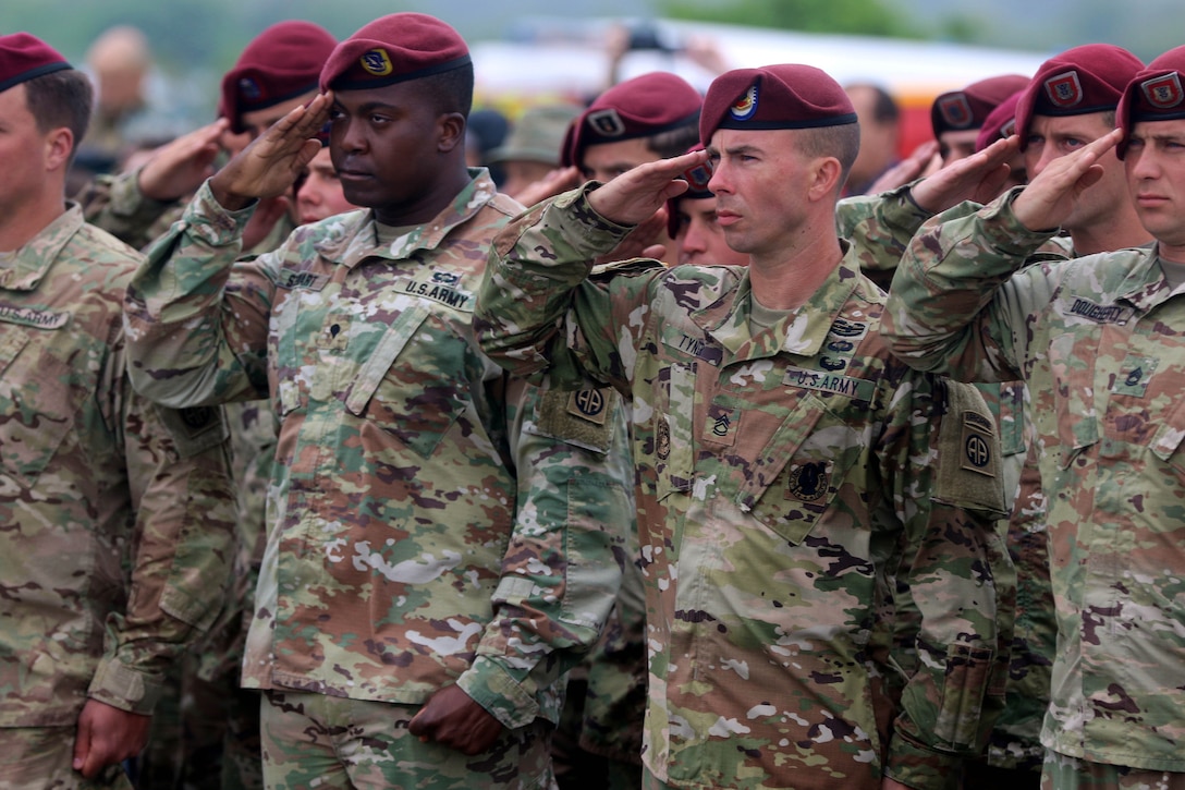 Soldiers render salutes during the 74th D-Day commemoration ceremony.
