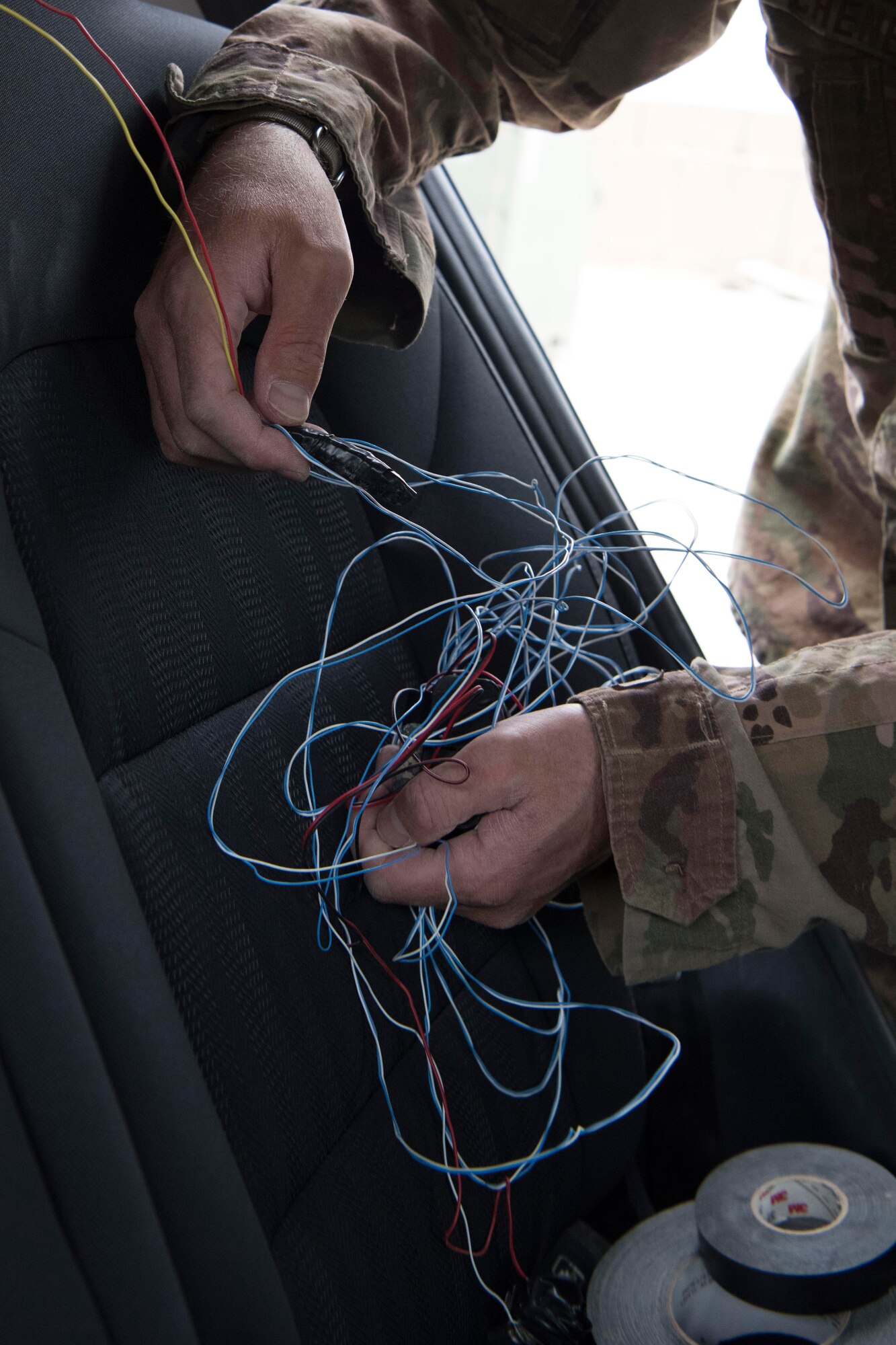 Tech. Sgt. Noah Cheney, 332nd Expeditionary Civil Engineer Squadron Explosives Ordnance Disposal Unit NCO in charge of training, hides wires of an inert improvised explosive device in a car in preparation for an exercise at an undisclosed location in Southwest Asia, May 28, 2018.