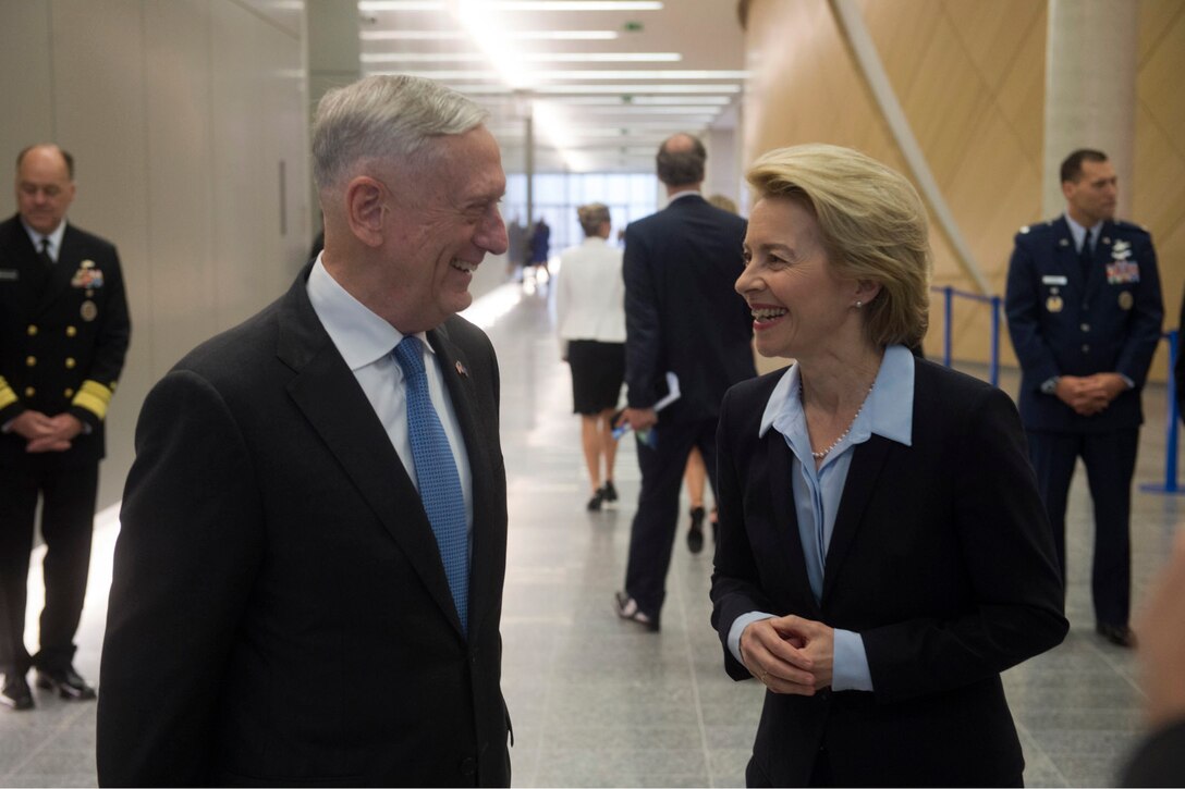 Defense Secretary James N. Mattis talks with his German counterpart in a hallway.