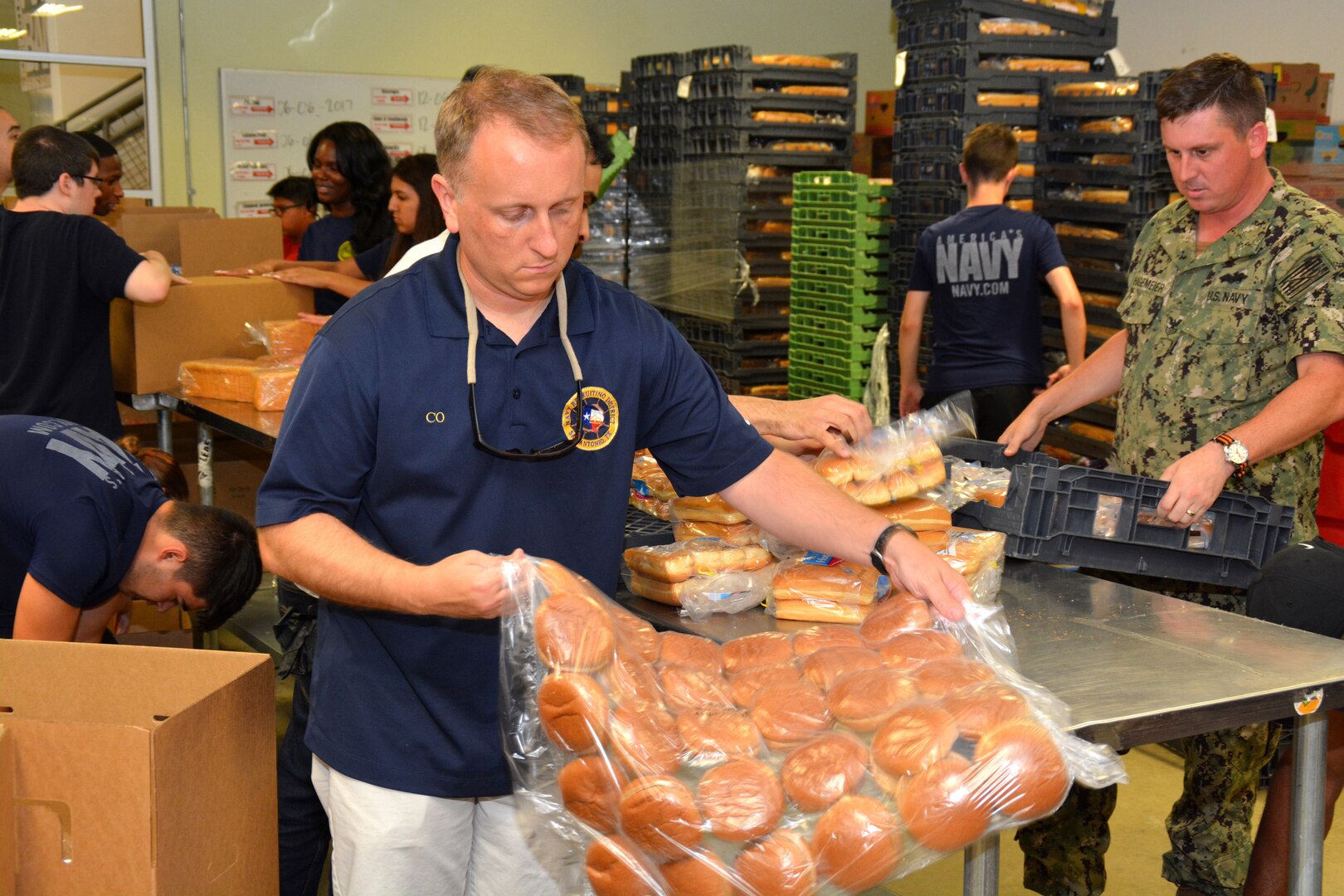 Cmdr. Jeffrey Reynolds, commanding officer of Navy Recruiting District San Antonio, volunteers at the San Antonio Food Bank during a Delayed Entry Program meeting June 6.  During the event, recruiters, along with more than 60 future Sailors and other volunteers, filled 575 bags of produce and sorted 19,447 pounds of food which will provide 15,558 meals for needy families.  The purpose of the volunteerism was to instill the “Whole Sailor Concept.”