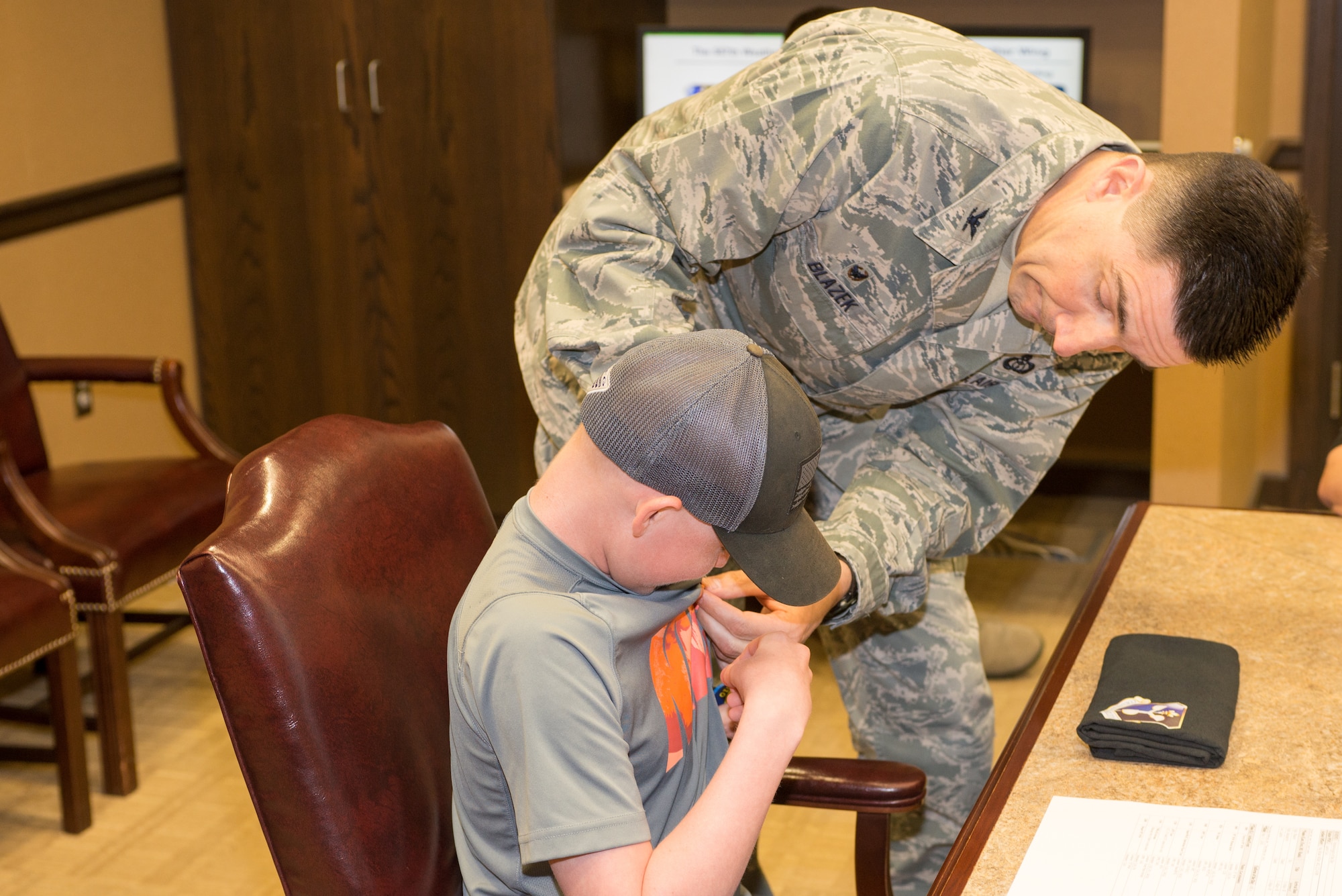 Mason Ogle receives an Air Force Meteorology occupational badge from Col. Thomas Blazek, 1st Weather Group commander, May 11, 2018, at Offutt Air Force Base, Nebraska. Mason, who is battling cancer, visited the 557th Weather Wing to learn more about meteorology and Air Force Weather. (U.S. Air Force photo by Paul Shirk)