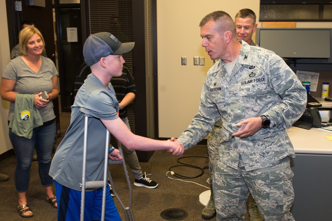 Mason Ogle is coined by Col. Steven Dickerson,  557th Weather Wing commander, May 11, 2018, at Offutt Air Force Base, Nebraska. Mason, who is battling cancer, wants to pursue a career in meteorology. (U.S. Air Force photo by Paul Shirk)
