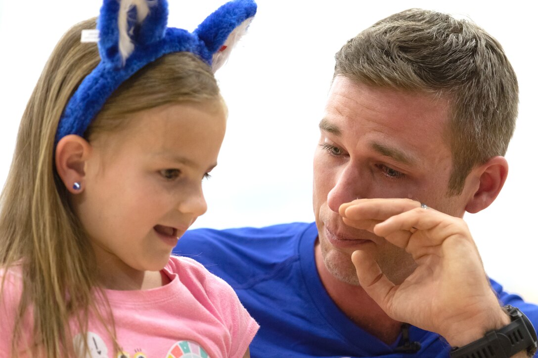 An airman cries while speaking to a child.