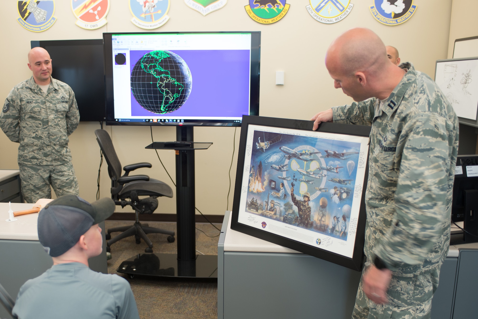 Capt. Dan Alexander, 1st Weather Group executive officer, presents Mason Ogle with a signed lithograph donated by members of the 1st Weather Group May 11, 2018, at Offutt Air Force Base, Nebraska. Mason, who is battling cancer, learned about weather radar and how weather observations are made  during his visit. (U.S. Air Force photo by Paul Shirk)