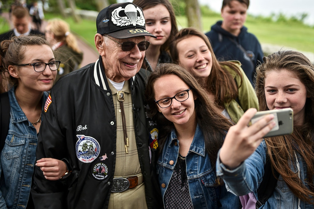 A group of girls take a selfie with a World War II veteran.