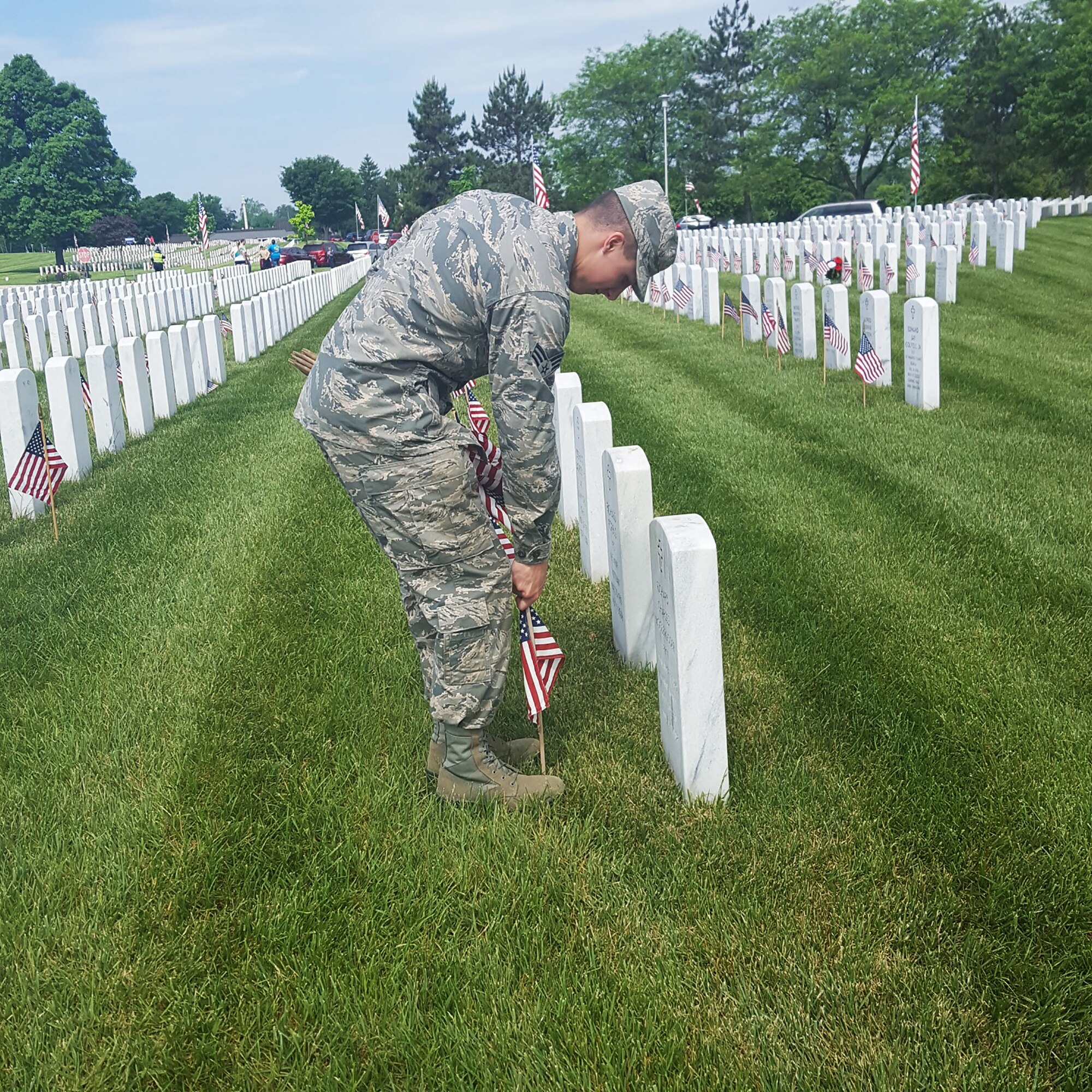 Senior Airman Millar, assigned to the 14th Intelligence Squadron, 655th Intelligence, Surveillance and Reconnaissance Group, plants an American flag on the grave of a servicemember during a Memorial Day service at the Dayton Veteran's Cemetery, Dayton, Ohio, May 28, 2018.