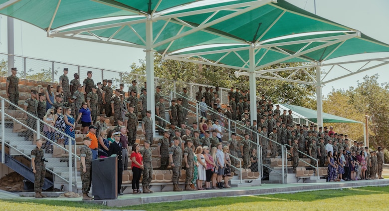The audience stands for the Marines Hymn during 1st Battalion, 7th Marine Regiment’s change of command ceremony aboard the Marine Corps Air Ground Combat Center, Twentynine Palms, Calif., June 4, 2018. The change of command ceremony ensures that the unit and its Marines are never without official leadership, and also signifies an allegiance of Marines to their unit’s commander. (U.S. Marine Corps photo by Lance Cpl. Rachel K. Porter)