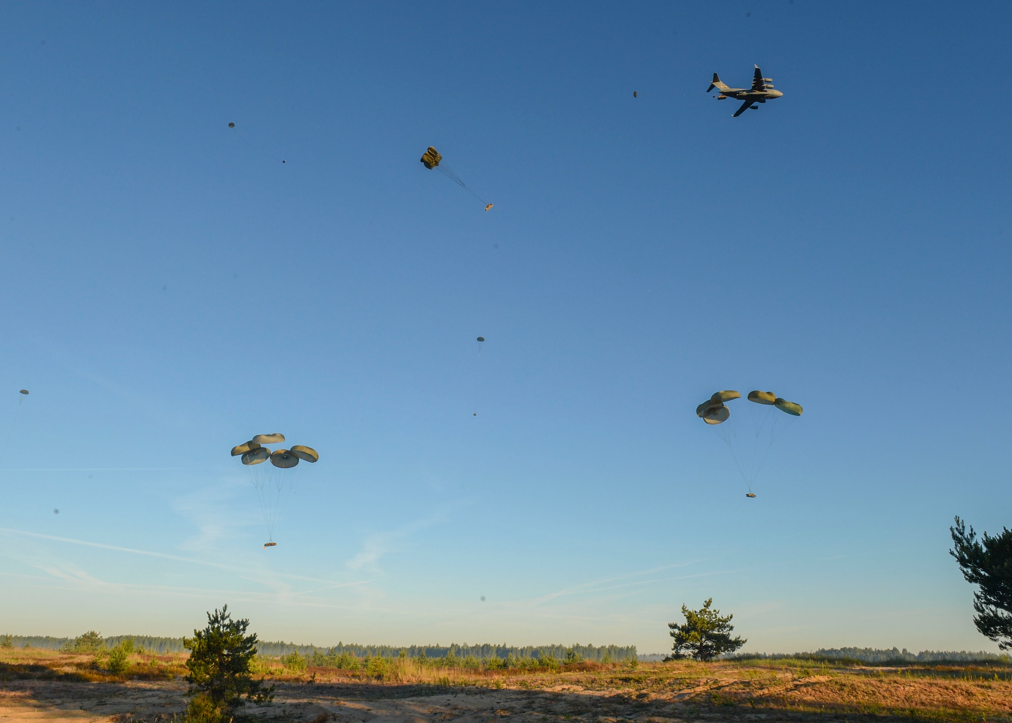 A U.S. Air Force C-17 Globemaster drops supplies over a drop zone in Adazi, Latvia, June 9, 2018. Four aircraft from the 62nd Airlift Wing at Joint Base Lewis-McChord, Washington and four aircraft from the 437th Airlift Wing at Joint Base Charleston, South Carolina provided support to exercise Swift Response 18. Swift Response included approximately 2,300 participants from seven allied nations to help train the U.S. Global Response Force, led by the U.S. Army’s 82nd Airborne Division, in Joint Forcible Entry operations. (U.S. Air Force photo by Staff Sgt. Jimmie D. Pike)