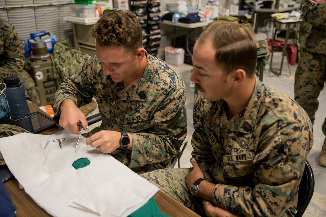 HM2 Caleb Beattie (left), and HM2 Matthew Hart (right), corpsmen with 4th Medical Battalion, 4th Marine Logistics Group, practice stitching a running and an interrupted suture during Integrated Training Exercise 4-18 in Twentynine Palms, California, on June 8, 2018. ITX 4-18 allows Reserve Marines and Sailors to train in realistic environments under realistic conditions, ensuring Marines and Sailors maintain the highest levels of proficiency and readiness for worldwide deployment and the ability to work as a Marine Air Ground Task Force. (Photo by U.S. Marine Lance Cpl. Samantha Schwoch/released)