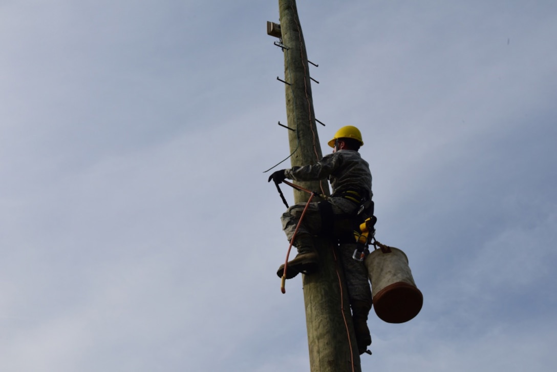 Staff Sgt. Jeremy Newton, an installations technician with the 211th Engineer Installation Squadron, Fort Indiantown Gap, Pennsylvania, climbs a telephone pole during the squadron competition June 9, 2018. Newton carried cables up the pole to attach in order to establish a connection. (U.S. Air National Guard photo by Senior Airman Julia Sorber/Released)