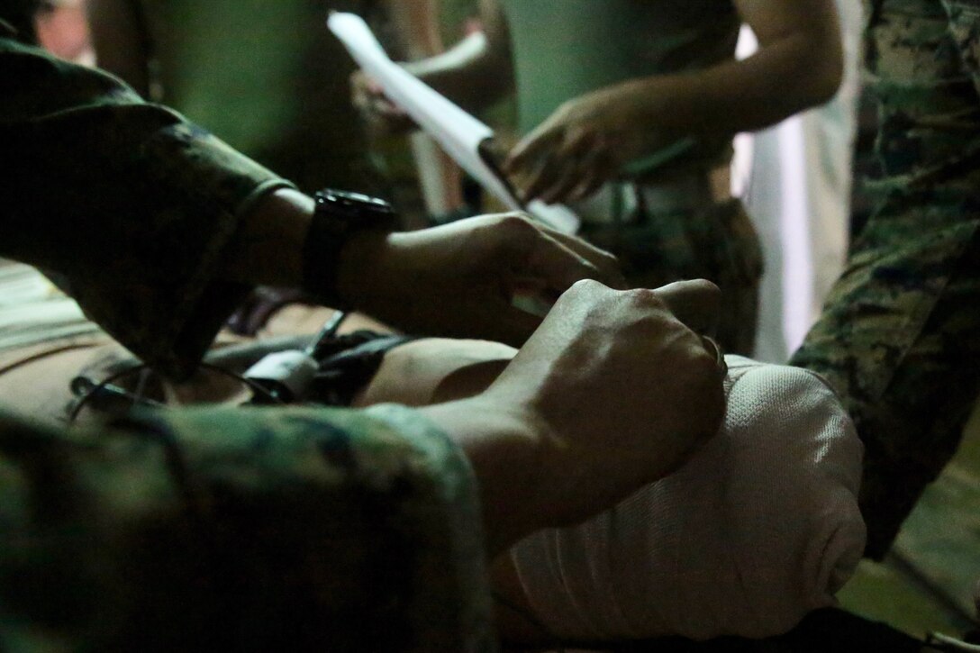 Navy Hospitalman 3rd Class John Ong wraps an amputation wound during a medical simulation at Kin Blue, Okinawa, Japan, June 6, 2018. The simulation is part of Exercise Inochi No Onjin, which increased competency of medical units' patient evacuation capabilities, command and control, medical regulating, and role-two capabilities. Ong, from Subic Bay, Philippines, is a field medical corpsman with 3rd Medical Battalion, 3rd Marine Logistics Group. (U.S. Marine Corps photo by Lance Cpl. Harrison Rakhshani)