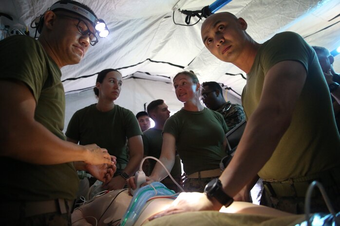 Navy field medical corpsmen with 3rd Medical Battalion, 3rd Marine Logistics Group provide emergency care to a dummy at Kin Blue on Okinawa, Japan, June 6, 2018. The simulation is part of Exercise Inochi No Onjin, which increased competency of patient evacuation, command and control medical regulating, and role-two capabilities in a joint environment.  3rd Medical Battalion is responsible for providing direct and general health service support to III Marine Expeditionary Force. (U.S. Marine Corps photo by Lance Cpl. Harrison Rakhshani)
